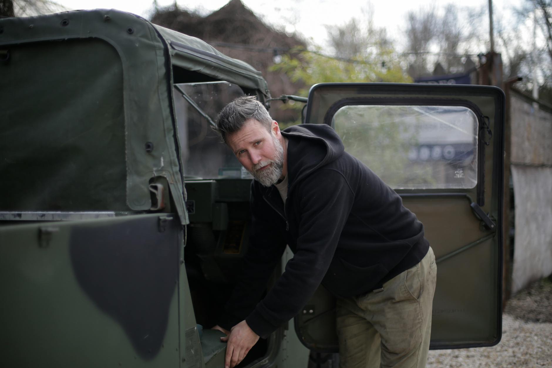 Mechanik z brodą ogląda podzespoły auta terenowego przed warsztatem