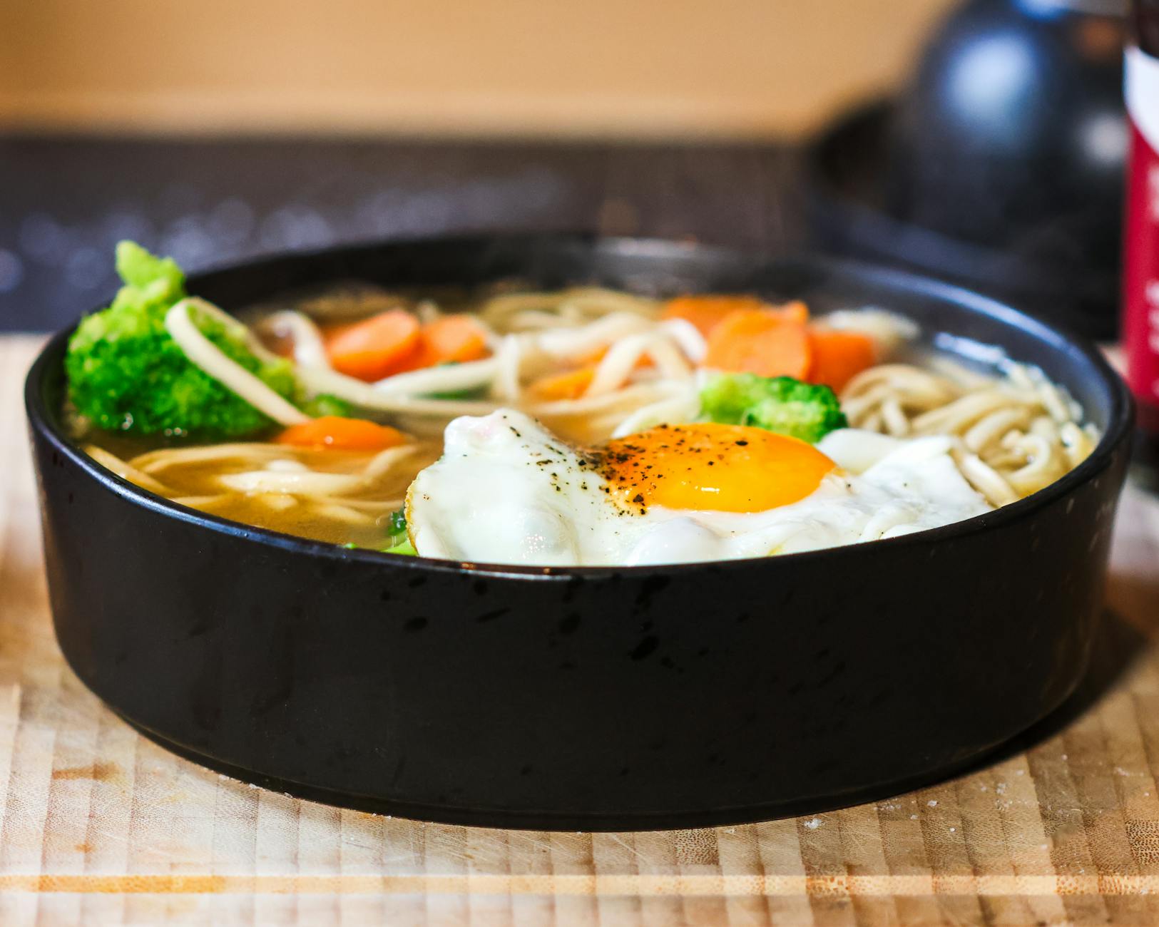 Miska domowego ramenu z jajkiem sadzonym, makaronem i świeżymi warzywami