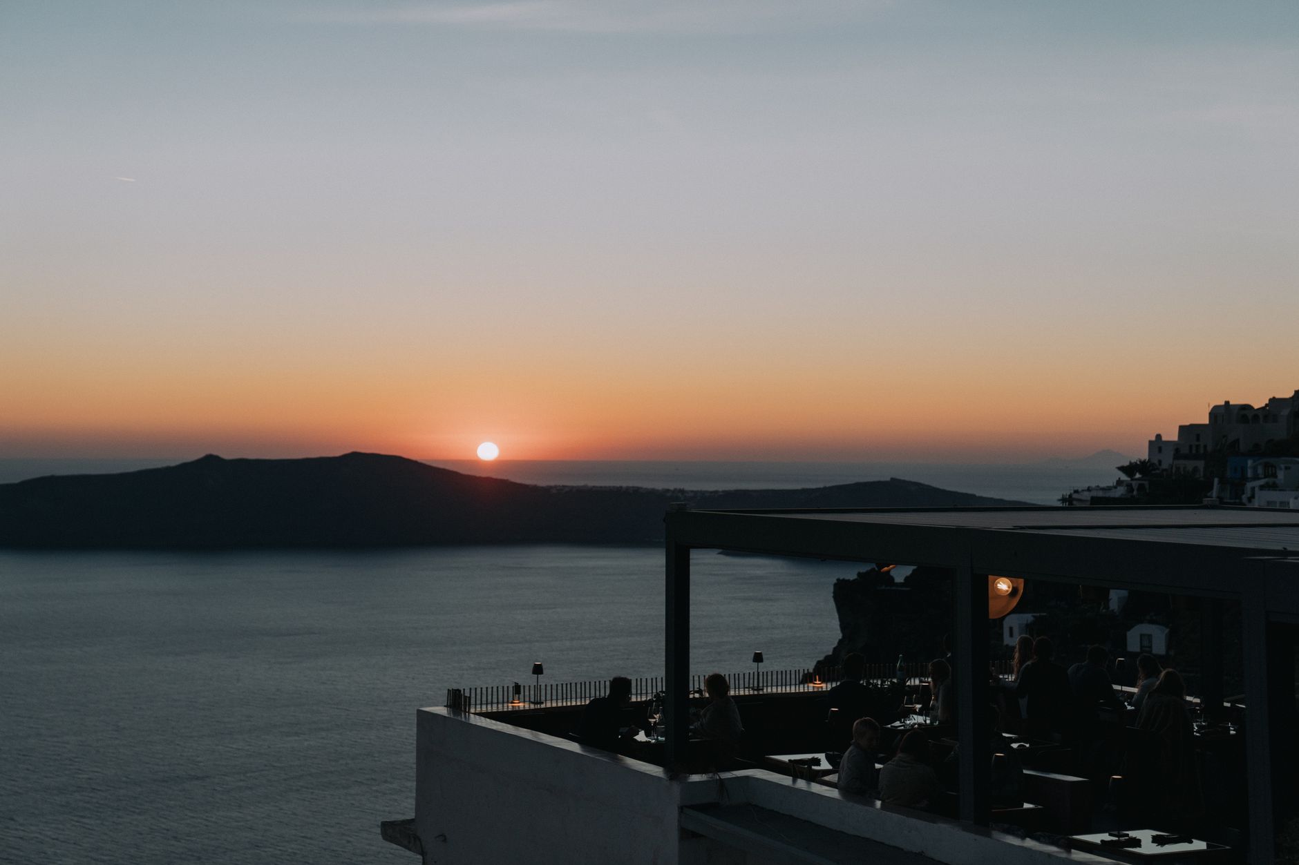 Zachód słońca w kawiarni na Santorini, sylwetki ludzi nad morzem